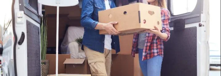 Zwei Personen tragen Umzugskarton in Transporter